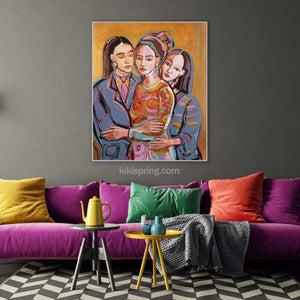 Colorful painting of three women hugging on a gray wall above a purple sofa with colorful cushions.
