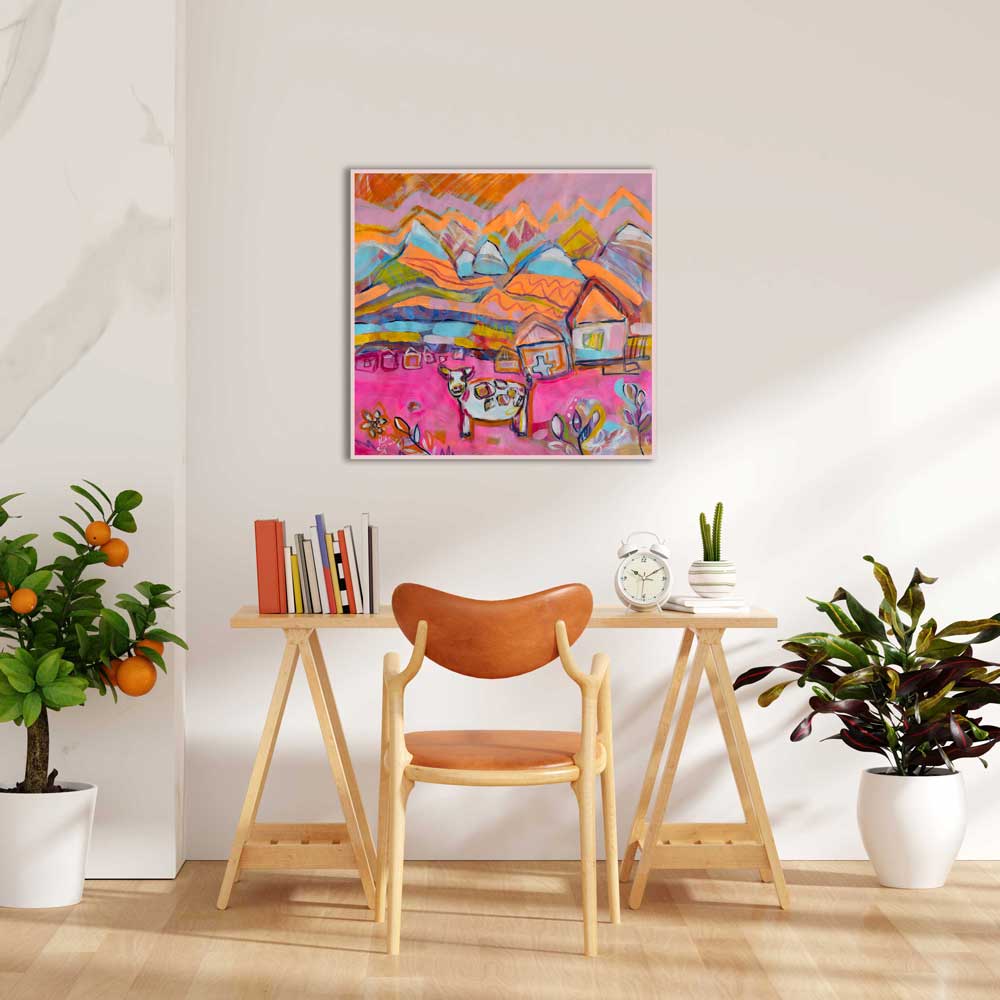 Colorful abstract painting on a wall above a wooden table with a chair, plants, and books.