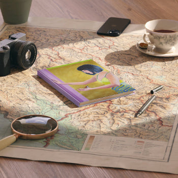 Notebook with a colorful cover on a map with a camera, phone, and tea cup nearby.