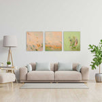 Load image into Gallery viewer, Living room with a beige sofa, three abstract paintings on the wall, and a lamp.
